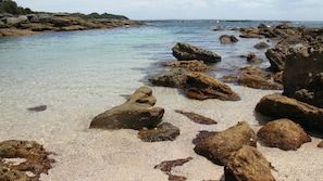Una costa rocciosa con acque limpide e ciottoli.