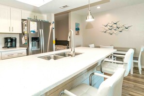 A modern kitchen with a stainless steel refrigerator, a coffee maker, and a sink.