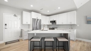 A modern kitchen with white cabinetry, stainless steel appliances, and a central island with bar stools. - 🏖️Just Renovated! Amazing Penthouse Unit Breathtaking Views of Ocean, Bay, Inlet🏖️ (Ocean City)