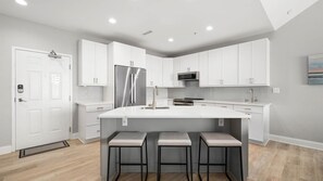 A modern kitchen with white cabinetry, stainless steel appliances, and a central island with bar stools. - 🏖️Just Renovated! Amazing Penthouse Unit Breathtaking Views of Ocean, Bay, Inlet🏖️ (Ocean City)