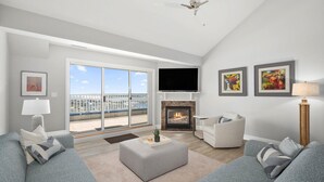 A modern living room with a fireplace, a flat-screen TV, and a balcony with a view of the city. - 🏖️Just Renovated! Amazing Penthouse Unit Breathtaking Views of Ocean, Bay, Inlet🏖️ (Ocean City)