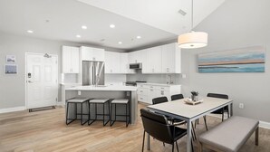 A modern kitchen with white cabinets, stainless steel appliances, and a dining area with a table and chairs. - 🏖️Just Renovated! Amazing Penthouse Unit Breathtaking Views of Ocean, Bay, Inlet🏖️ (Ocean City)