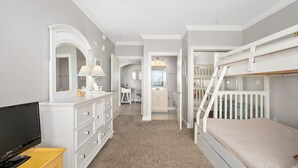 A bedroom with a bunk bed, a dresser, a TV, and a bathroom visible through an open door. - 🏖️Just Renovated! Amazing Penthouse Unit Breathtaking Views of Ocean, Bay, Inlet🏖️ (Ocean City)