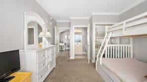 A bedroom with a bunk bed, a dresser, a TV, and a bathroom visible through an open door. - 🏖️Just Renovated! Amazing Penthouse Unit Breathtaking Views of Ocean, Bay, Inlet🏖️ (Ocean City)
