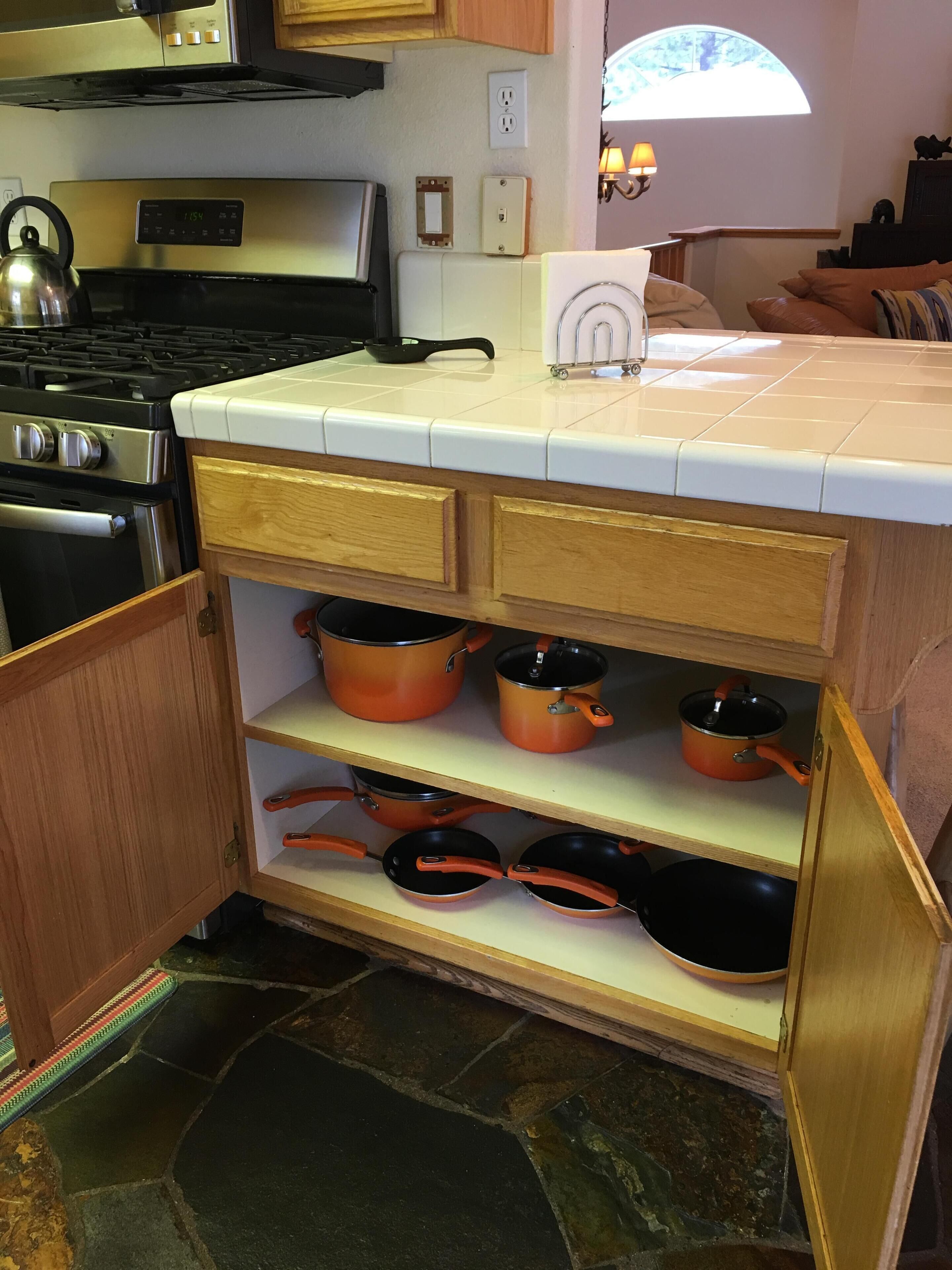 A kitchen with wooden cabinets, a stove, and a countertop with a kettle.