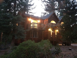 A two-story log cabin with a balcony and large windows, surrounded by dense forest. - Cozy Kings Beach cabin close to downtown and Lake (Tahoe Vista)