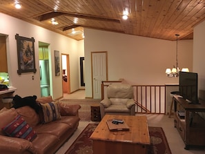 A living room with a leather sofa, a wooden coffee table, a TV stand, and a chandelier. - Cozy Kings Beach cabin close to downtown and Lake (Tahoe Vista)