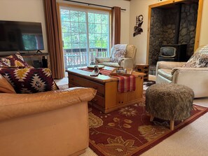 A cozy living room with a sofa, ottoman, and a television. - Cozy Kings Beach cabin close to downtown and Lake (Tahoe Vista)
