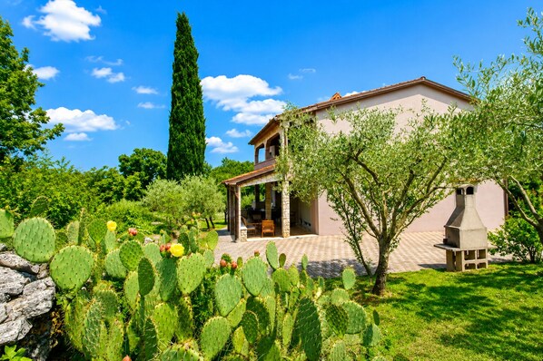 Una casa con un patio, rodeada de cactus y árboles.