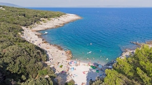 A coastal beach with clear blue waters, sandy shores, and lush greenery. - Holiday Apartment "Nikolina 1" with spacious garden (Rakalj)