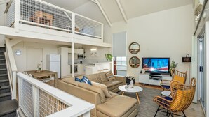 Un vaste espace de vie doté d’un haut plafond, une cuisine, un coin repas et un balcon offrant une vue agréable.