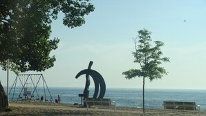 Una playa con un columpio, bancos y una gran escultura abstracta.