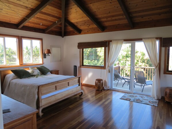 A bedroom with a wooden bed, a nightstand, a dresser, and a large window with curtains.