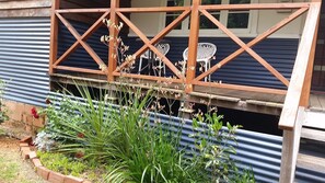 A wooden structure with a metal roof, possibly a porch or deck, with a garden area in front. - Dwellingup Escape. Large home opp Forest. Sleeps 8, 1.5 Bathrooms. Games Rm (Dwellingup)
