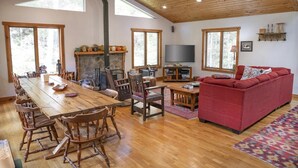 A spacious living room with a wooden dining table, red sofa, and a fireplace. - STUNNING  VACATION AND SKI HOME - Hudson Valley, Woodstock, Hunter (Palenville)