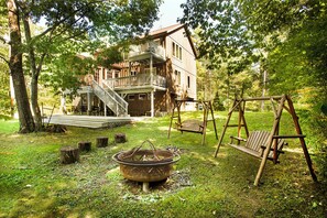 Escape to a serene cabin surrounded by lush greenery, featuring a balcony and a fire pit for cozy gatherings.