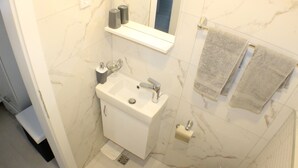 A bathroom with a white sink, mirror, and towel rack. - Danica - apartment 003 (Promajna)