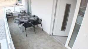 A small dining area with a table and four chairs, a sliding glass door, and a tiled floor. - Danica - apartment 003 (Promajna)