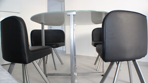 A modern dining area with a glass table and four black chairs. - Danica - apartment 003 (Promajna)