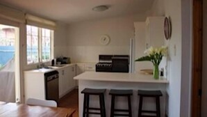 A compact kitchen with a central island, a dishwasher, and a clock on the wall.