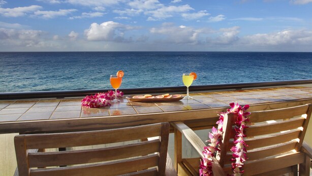 A wooden bench with a table in front, overlooking a body of water. - Absolutely Stunning Oceanfront Condo! (Koloa)