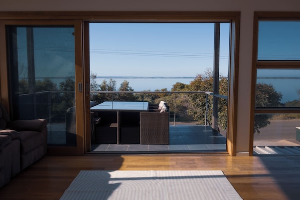 Une chambre moderne dotée d’une porte-fenêtre coulissante donnant sur un balcon avec vue sur la mer.