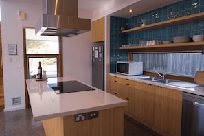 A modern kitchen with a central island, stainless steel appliances, and blue-tiled backsplash.