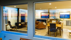 Un salon moderne avec une cheminée, un canapé, un coin repas et une cuisine.