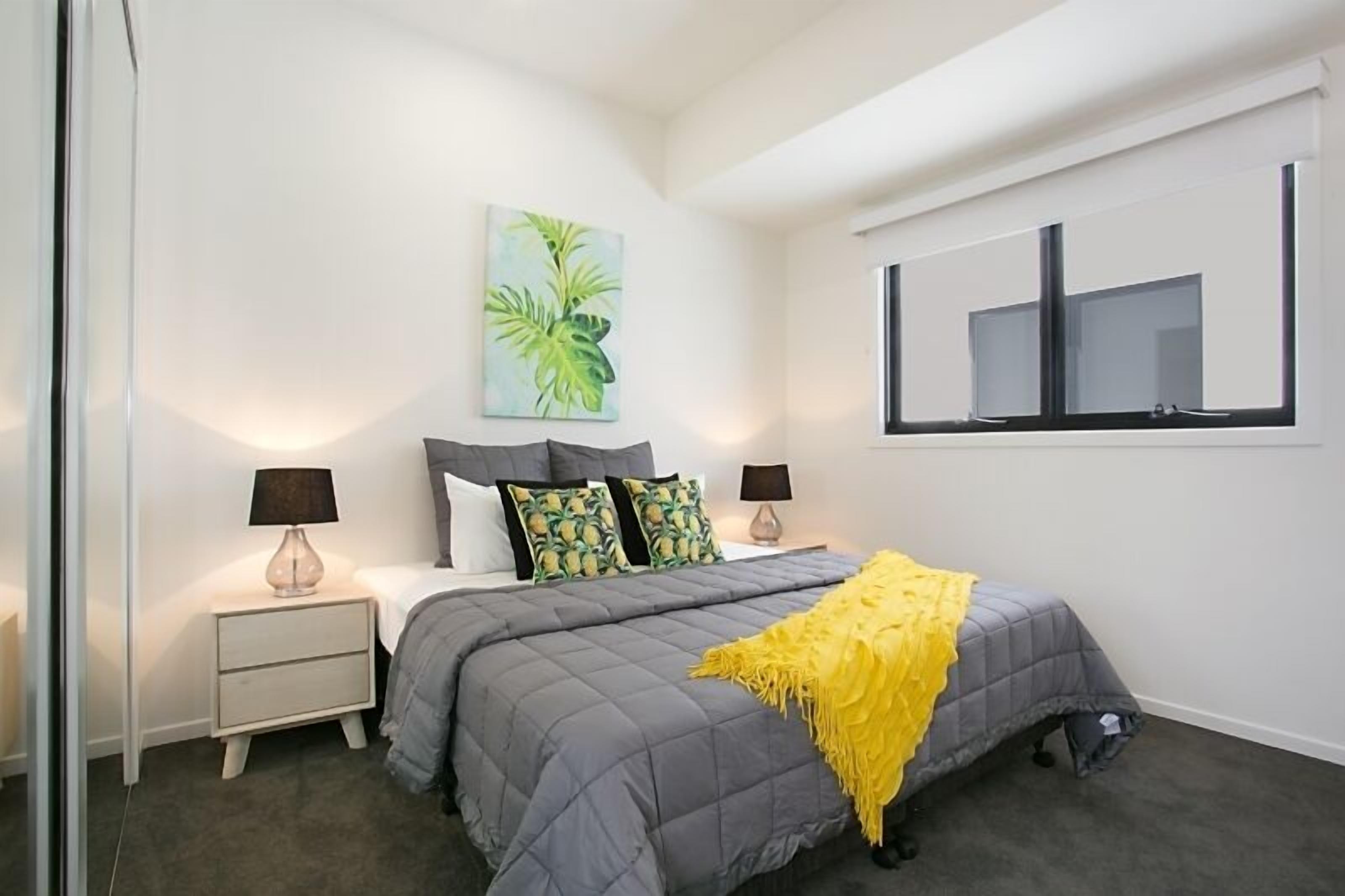 A bedroom with a bed, nightstands, lamps, a painting, and a window.