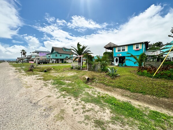 A coastal road with houses, including a blue building with a sign that reads "The Beach Club." - Unique charming coastal cottage (Surfside Beach)
