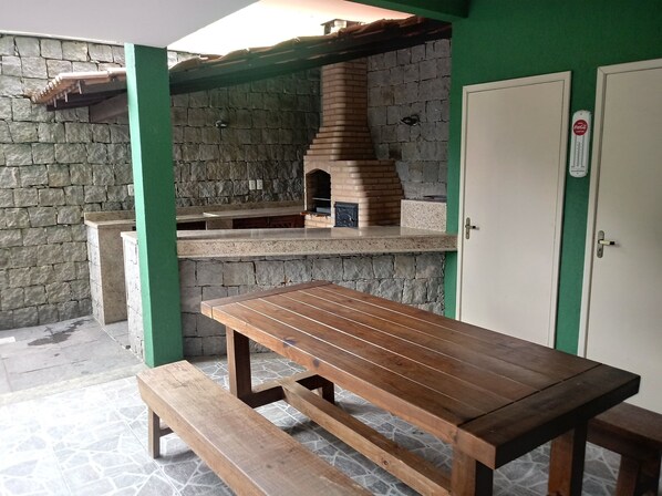 A stone wall with a brick oven, a wooden table, and benches. - Feet in the Sand - Angra dos Reis - Turtle Beach (Monsuaba)