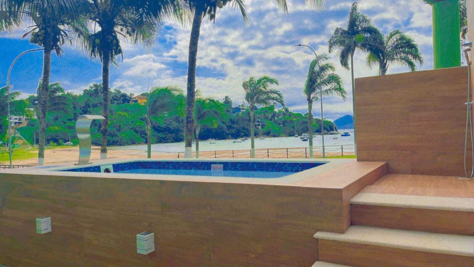 A swimming pool with steps leading up to it, surrounded by palm trees and a view of the sea.