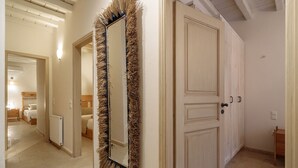 A hallway with a large mirror, a door, and a bed in the background.
