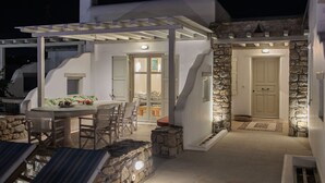 A covered outdoor dining area with stone walls and a white building.