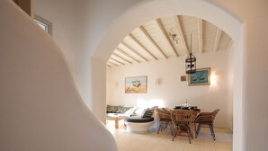 An interior with a dining area featuring wicker chairs and a table, a sofa, and a ceiling fan.