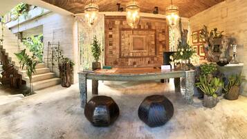 Experience the warm, natural ambiance of our lobby, featuring a large table, lush greenery, and a unique sculpture.