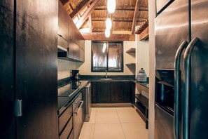 A compact kitchen with dark wooden cabinets, stainless steel appliances, and a visible window.