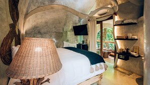A bedroom with a bed, a lamp, a TV, and a shelf with towels. - Orchid House Tulum Jungle (Tulum)