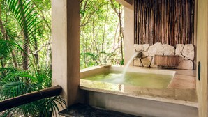 A hot tub with a stone wall and a wooden fence in a lush, green environment. - Orchid House Tulum Jungle (Tulum)
