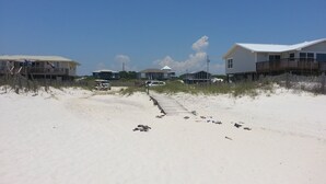 A beachside property with a sandy path leading to a wooden deck, surrounded by beach houses and dunes. - Great Gulf Views and easy walk to the beach.  Dog Friendly! (Gulf Shores)