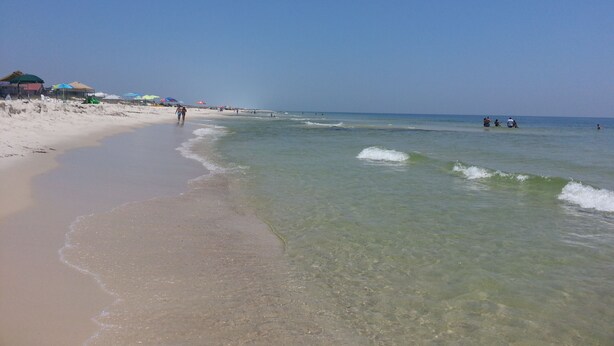 A beach with clear shallow waters, umbrellas, and people. - Great Gulf Views and easy walk to the beach.  Dog Friendly! (Gulf Shores)