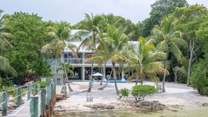 Ein Strandgrundstück mit Holzterrasse, Pool und Palmen.