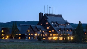 A large, multi-story lodge with a steep roof and multiple chimneys, surrounded by a grassy area and trees. - Charming Jackson Hole cabin bordering Grand Teton National Park (Jackson)