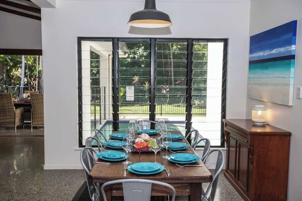 Comedor con una mesa de madera dispuesta para seis personas, rodeado de sillas metálicas.