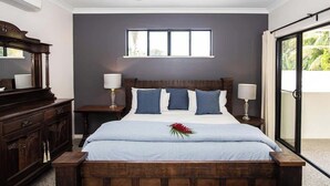 Ein Schlafzimmer mit einem großen Bett, einem Deckenventilator, einem Fenster und Blick auf Grün.