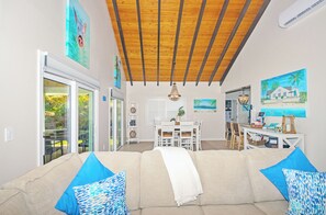 Relax in this inviting living area with a sofa, dining table, and console table, surrounded by artwork and a sliding door to the outdoor patio.