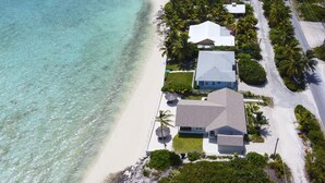 Oversigtsbillede af en ejendom ved kysten med et stort hus, en mindre bygning og en strand.