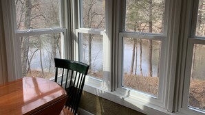 A room with a view of a lake and trees through large windows.