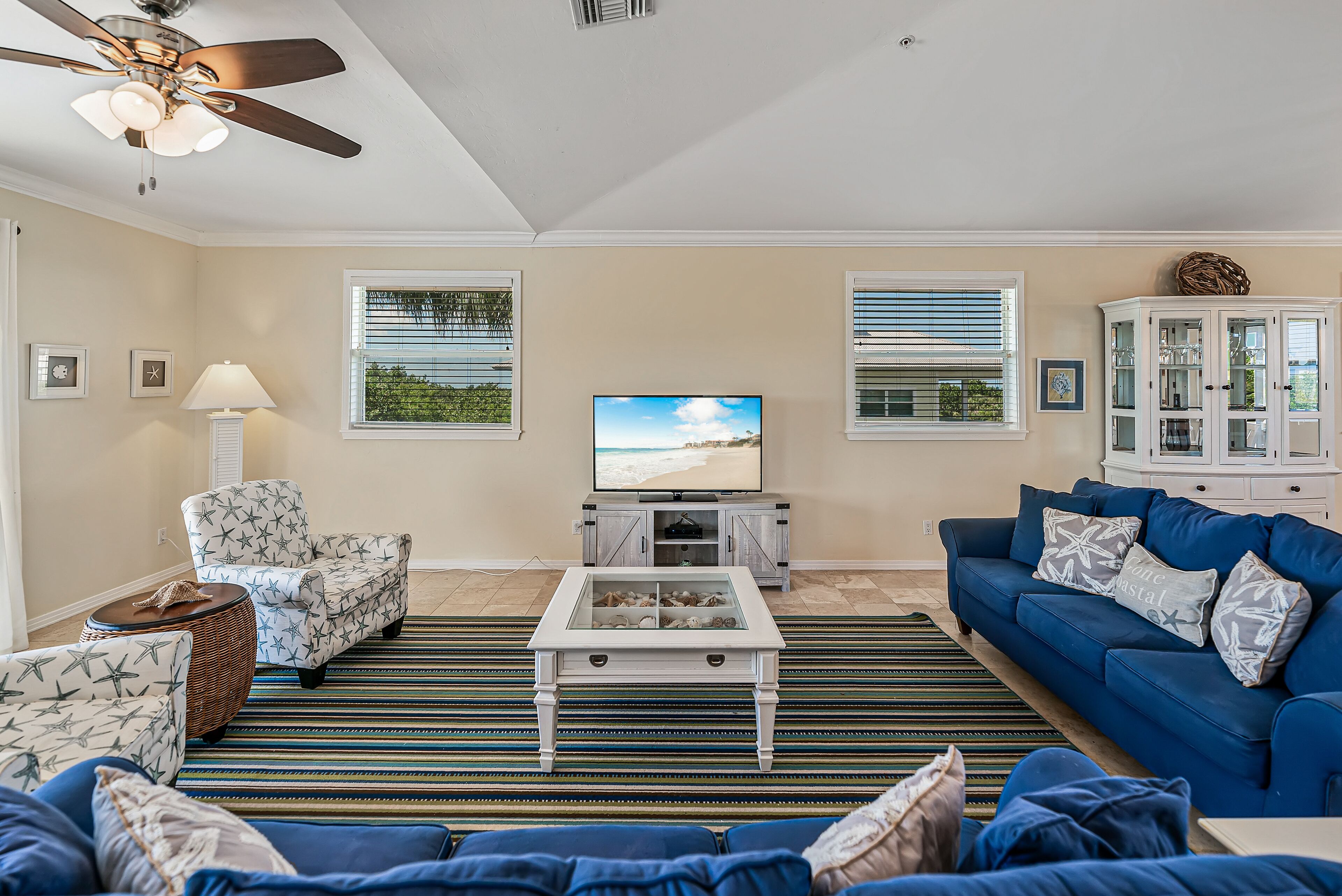 A living room with a television, sofa, armchair, and a ceiling fan.
