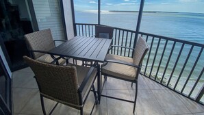 Un balcon avec une table et des chaises, donnant sur une étendue d’eau.